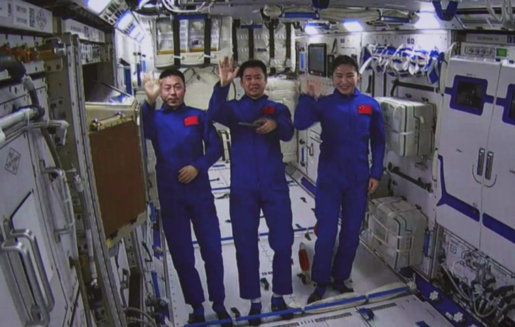 An image taken off the screen at the Beijing Aerospace Control Center shows Chinese astronauts from left, Cai Xuzhe, Chen Dong and Liu Yang wave from inside the Wentian lab module on Monday, 