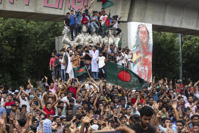 Protesters climb a public monument as they celebrate the news of Prime Minister Sheikh Hasina's resignation, in Dhaka, Bangladesh, Monday, Aug. 5, 2024. (AP Photo)