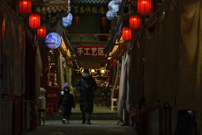 FILE - A man and a child wearing face masks walk by shuttered stores on Jan. 3, 2023, which would be selling souvenirs in Qianmen, a popular tourist spot in Beijing. AP/RSS Photo