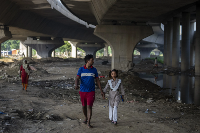 Shiv Kumar, left, accompanies his daughter Garima, 10, to her school as they walk on the flood plain of Yamuna River, in New Delhi, India, Friday, Sept. 29, 2023. AP/RSS Photo