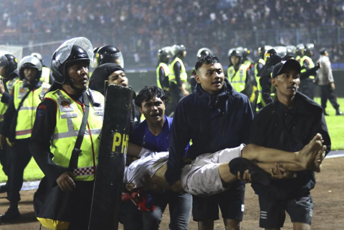 Soccer fans carry an injured man following clashes during a soccer match at Kanjuruhan Stadium in Malang, East Java, Indonesia, Saturday, Oct 1, 2022. (AP/RSS Photo)
