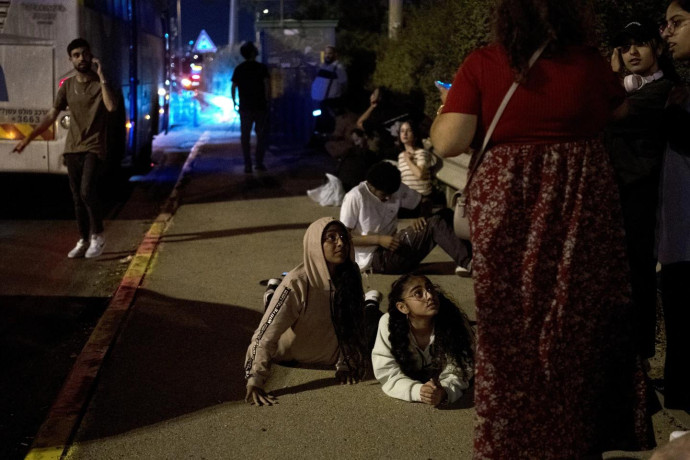 Israelis wait to re-board their bus after projectiles were launched from Iran are being intercepted in the skies over in Rosh HaAyin, Israel, Tuesday, Oct. 1, 2024. (AP Photo)