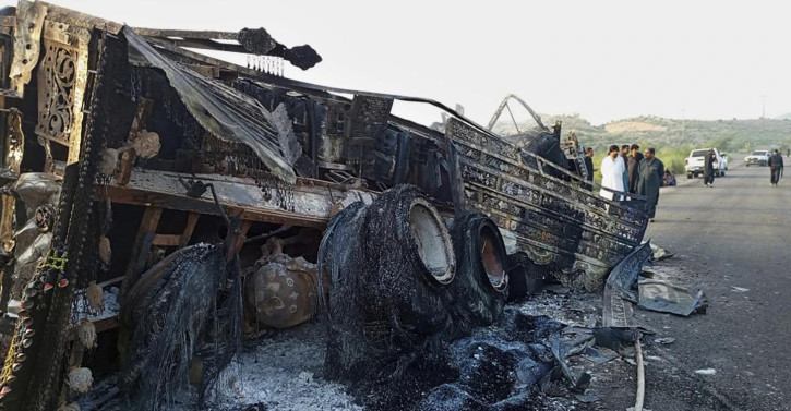 People look at a burnt vehicle which was torched by gunmen after they killed passengers at a highway in Musakhail, a district in Baluchistan province in restive southwestern Pakistan, Monday, Aug. 26, 2024. (AP Photo)