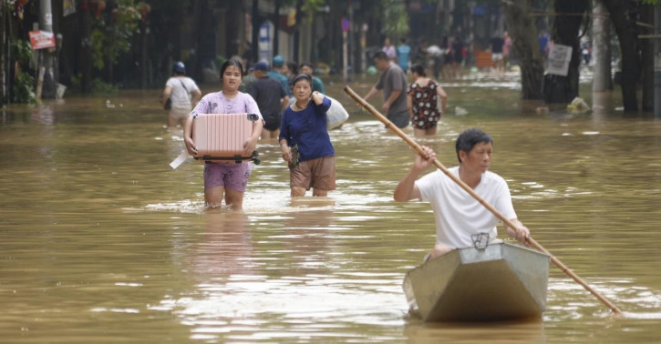 People carrying belongings wade in a flooded street in the aftermath of Typhoon Yagi, in Hanoi, Vietnam on Thursday, Sep. 12, 2024. (AP Photo)