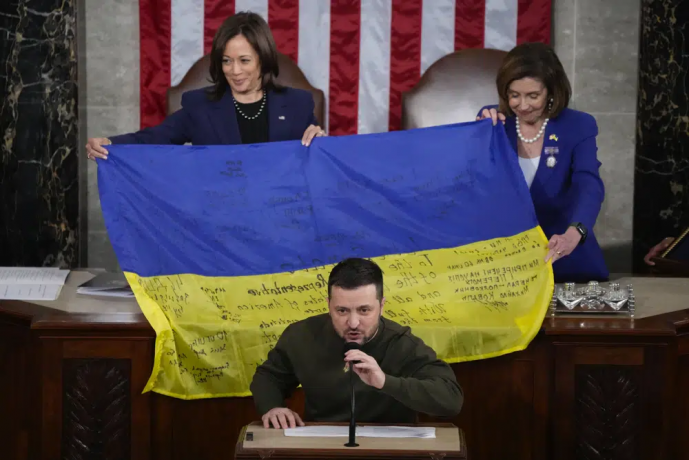 Vice President Kamala Harris and House Speaker Nancy Pelosi of Calif., right, react as Ukrainian President Volodymyr Zelenskyy presents lawmakers with a Ukrainian flag autographed by front-line troops in Bakhmut, in Ukraine's contested Donetsk province. AP/RSS Photo